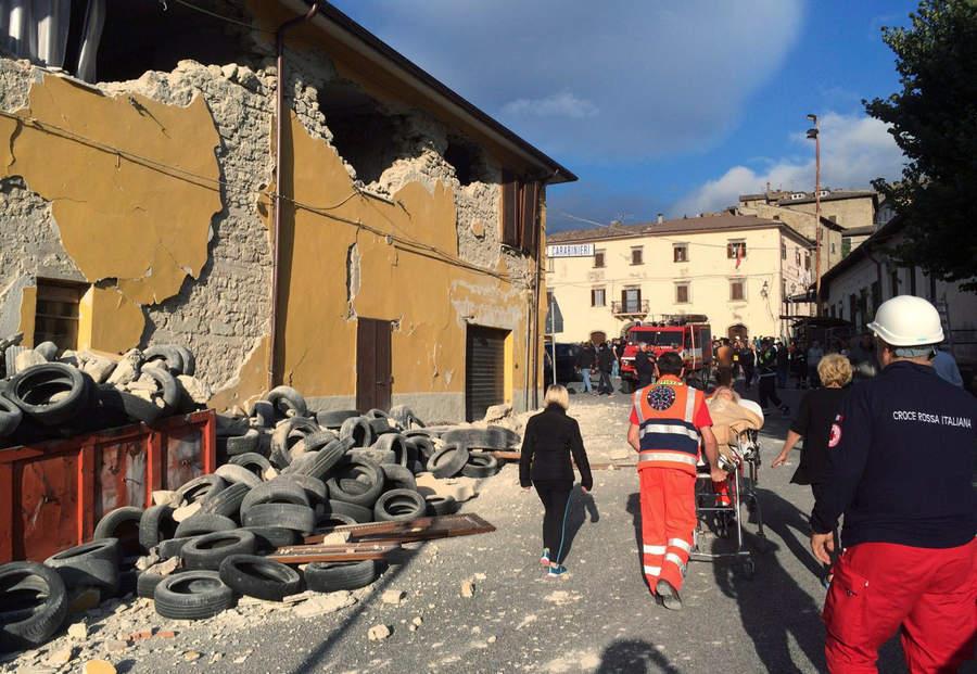 Rescuers and people walk along a road following an earthquake in Accumoli di Rieti, central Italy