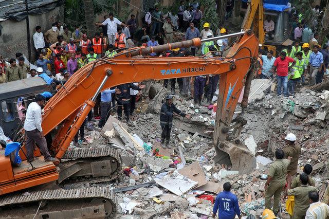 Firefighters and rescue workers remove the debris as they search for survivors at the site of a collapsed building in the suburbs of Mumbai