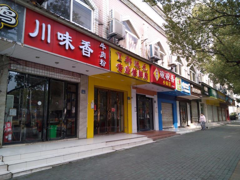 A woman walks past closed shops in Wuhan