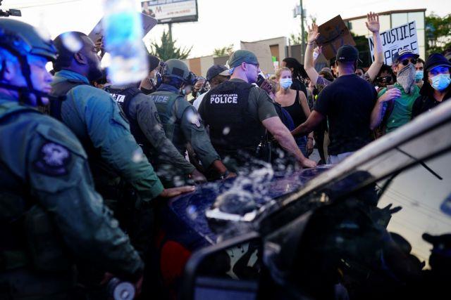 Police officers escort a police SUV from a crowd of protesters while bottles of water are thrown at them during a rally against racial inequality and the police shooting death of Rayshard Brooks, in Atlanta